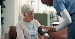 Nurse, old woman and blood pressure monitor on couch for assessment, explain or hypertension in retirement home. Senior person, caregiver and show results with tech, exam or healthcare test in house
