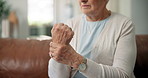 Senior woman, hands and wrist pain with injury on sofa for arthritis or carpal tunnel syndrome. Closeup, elderly or female person with sore arm for joint inflammation or muscle tension in house