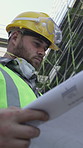 Blueprint, reading or man on construction site for inspection,  building schematic or safety compliance. Project development, outdoor or contractor with floor plan, infrastructure evaluation or below