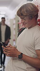 School, typing or teenager with phone in hallway, academy learning platform or check social media on break. Message notification, texting or boy with mobile to browse internet, education or research 