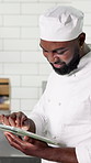 Tablet, black man and chef in kitchen, typing and digital app for recipe, food blog and network. Employee, smile and African person with tech, checklist and online order for meal, menu or ingredients