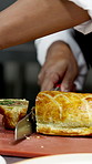 Hands, chef and cutting pie in kitchen, serving and meal prep for order, cuisine or service at diner. Person, cooking and beef wellington with knife, gourmet dish and food with career at restaurant