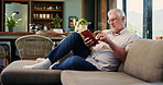 Reading, book and old man on sofa in home to enjoy literature, story and literacy on weekend. Retirement, living room and elderly person with novel for hobby, fiction and relax for knowledge in house