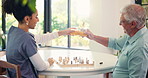 Chess, old man and caregiver with board game for toast, challenge and winning strategy. Solution, decision and elderly person with nurse for cognitive skills, tactics and drinks in retirement home