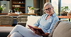 Senior woman, relax and reading book on couch in home with story, literature and poetry for language. Elderly person, information and glasses with novel, fiction and smile in living room at apartment
