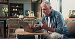 Reading, laptop and tablet with old man on sofa for mortgage payment, retirement funds and planning. Online banking, digital invoice and research with senior person in home for pension account