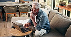 Typing, laptop and thinking with old man on sofa for mortgage payment, retirement funds and planning. Online banking, digital invoice and vision with senior person in home for pension account