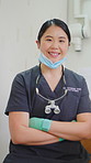 Woman, dentist and face with arms crossed, smile and confidence with career at oral care clinic. Person, dental surgeon and happy in portrait with pride, scrubs or wellness at hospital in Thailand