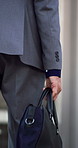 Bag, hand and businessman walk in city for travel, morning commute and lawyer on urban journey. Case, person and professional outdoor on trip in town with back, pedestrian and legs of attorney