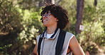 Man, hiking and smile with thinking in forest, sightseeing and backpack for adventure on summer vacation. Person, nature tourism and happy with perspective, trekking and outdoor in woods on holiday