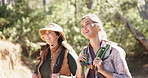 Friends, talking and hiking outdoor in nature with bag for tourist adventure, wellness and journey. Women, trekking and walking with backpack in forest for travel, holiday activity and conversation.