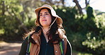 Woman, hiking and smile with thinking in forest, sightseeing and backpack for adventure on summer vacation. Person, nature tourism and happy with perspective, trekking and outdoor in woods on holiday
