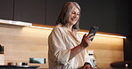 Phone, happy and senior woman in kitchen in home with social media, connectivity or texting. Smile, technology and elderly female person with cellphone for chatting on mobile app in apartment.