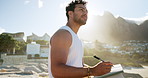 Beach, thinking and man writing in journal for emotions, mental clarity or self care on holiday. Pen, ideas and person with diary for reflection by ocean for calm, peace or mindfulness on vacation.