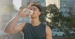 Man, fitness and drinking with water in city for workout break, hydration or recovery. Active, male person or runner with mineral liquid, bottle or aqua beverage for sustainability in an urban town