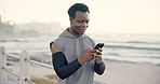 Fitness, ocean and black man with smartphone, smile and digital app to track progress. African person, training or athlete with cellphone, seaside or connection for social media or message to contact