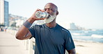 Drinking water, ocean and black man with fitness, break and exercise for health benefits. Mature person, beach and athlete with hydration, resting and thirsty with wellness, training and nutrition