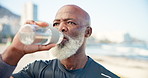 Senior black man, water bottle and fitness at beach, rest or space for wellness by sea. African person, drink and liquid for hydration, exercise and outdoor on break, ocean and training in summer