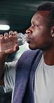 Black man, drinking water and towel at gym, tired and break with sweat, hydration and fitness at club. African person, fatigue and bottle for training, exhausted or rest for burnout at exercise class