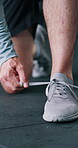 Workout, sneakers and hands with lace in gym, fitness preparation and indoor sports training for wellness. Getting ready, athlete or person tie shoes in health club, morning routine or start exercise