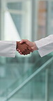 Doctors, shaking hands and agreement in hospital hallway with greeting, deal or welcome for hiring. People, medical staff and handshake for success, recruitment and thanks with onboarding at clinic