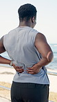 Fitness, man outdoor and back pain from exercise, difficult workout and problem on beach promenade. Active, person or athlete stretching with inflammation, strain and medical issue from spine injury.