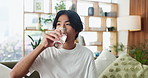 Water, pills and man on sofa in home for supplements, medication or sickness recovery in living room. Health drink, hydration and person with medicine for wellness with tablets or vitamins in house.