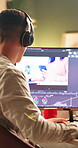 Video editor, online and man with headphones, computer screen or creative for post production on web. Back, editing and person with tech for content creation, social media and process with software