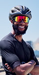 Black man, arms crossed and bicycle in city with sunglasses for exercise, smile and confidence on bridge. African person, bike and cycling with helmet, pride and training for cardio challenge in town