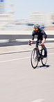 Athlete, man and speed on bicycle in city for cycling exercise, endurance challenge and motion blur. Fast cyclist, person and riding bike in road for triathlon training, sports performance or fitness