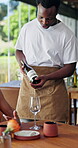 Waiter, customer and talk in restaurant with wine bottle, hospitality service and explain beverage info. People, employee and conversation with alcohol order, fine dining and drink recommendation.