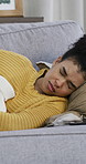 Sick woman, stomach ache and sofa with period cramps, discomfort or menstruation cycle in home. Tired, female person or lying with sore tummy bug or hot water bottle for indigestion or constipation