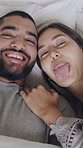 Couple, funny face and silly on bed, home and cuddle with partner on break, above or love in bedroom. Goofy, man and woman with smile, laughing and relax with spouse on weekend, humor and affection