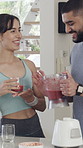 Happy couple, blender and glass with smoothie in kitchen for bonding, drinks and detox at house. Man, woman and hug with nutrition, diet or connection for relationship with thanks at apartment