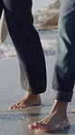 Happy, walking and feet of couple on beach for bonding on holiday, getaway and summer vacation. Dating, nature and man with woman by ocean for relationship, connection and relax outdoor with waves