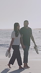 Happy, holding hands and couple on beach walking for bonding on holiday, getaway and vacation. Dating, nature and man with woman by ocean for relationship, connection and relax outdoor with waves