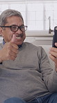 Old man, phone and wave for video call in home with smile, hello and contact on sofa in retirement. Elderly person, happy and thumbs up with smartphone, mobile app or virtual chat on couch in house