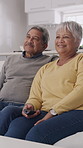 Old couple, laugh and watching tv on sofa in home with remote control, bonding and relax in lounge. Elderly man, woman and partner with embrace, streaming and subscription for movies in retirement
