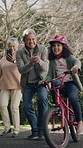 Grandparents, help and bike for picture, girl and learning for child development, smile and recording. Kid, senior woman and old man in street, granddaughter and bicycle for photo, memory and cycling