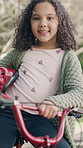 Happy, face and child with bicycle, outdoor and trip with eco friendly transport, helmet and safety. Park, girl and kid with bike for adventure, wellness and commuting on street, ride and hobby