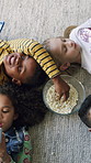 Children, friends and phone on floor in home with popcorn, above and bonding with games in living room. Kids, group and smartphone with mobile app, connection and eating snacks on carpet at house
