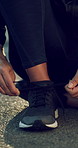 Woman, hands and tie shoelace for exercise start, preparation and safety for runner outdoor on road. Active, person and secure sneakers in street for fitness, beginning and getting ready for workout.