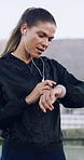 Fitness, runner and woman with smart watch in city for workout, progress or heart rate on app. Earphones, check results and person with tech for exercise goals, training and recovery time on road