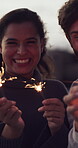 Outdoor, sparklers and face of happy couple on vacation,  anniversary trip and commitment celebration. Portrait, love and people laughing with fireworks for holiday memory, bonding and new year date