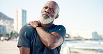 Senior man, shoulder pain and runner at beach with stress, injury or muscle fatigue with rest on promenade. African person, frustrated and exhausted with strain, sky and space for fitness by ocean