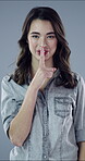 Face, woman and finger on lips in studio, confidential secret and sensitive information for silence. Portrait, private news and person with hush for unknown announcement, smile and gray background