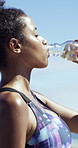 Fitness, woman and drinking water by ocean for health, wellness and smile on break with sweat. African person, exercise and athlete with bottle for hydration, nutrition and recovery with sea view