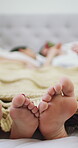 Couple, feet and relax on bed, home and bonding with partner on valentines day, commitment and love. Sleeping, together and people on break, closeup and roses in bedroom, romance or anniversary