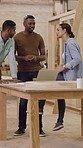 Carpentry, talking and people with laptop in workshop for furniture ideas, planning and woodworking project. Teamwork, carpenter and men with woman on tech for meeting, inspection or timber inventory