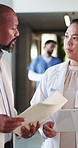 Doctors, paperwork and discussion with file in hospital for medical opinion, update or advice. Health team, people and meeting in clinic hallway with treatment feedback, surgery schedule or workflow